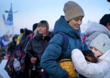 Молода дівчина з України чекає зі своєю матір'ю та собакою після перетину кордону з Польщею у 2022 році. Фото: PA
